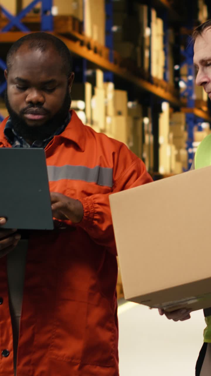 Vidéo verticale : Employés multiethniques triant des cartons dans un entrepôt industriel.