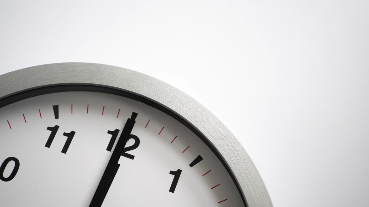 Close up of a white ticking clock on white background, pointing midnight