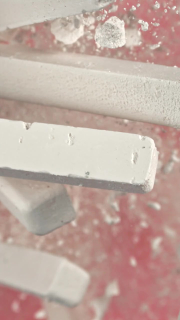 White Chalk Sticks Falling and Shattering into Dust on Red Background