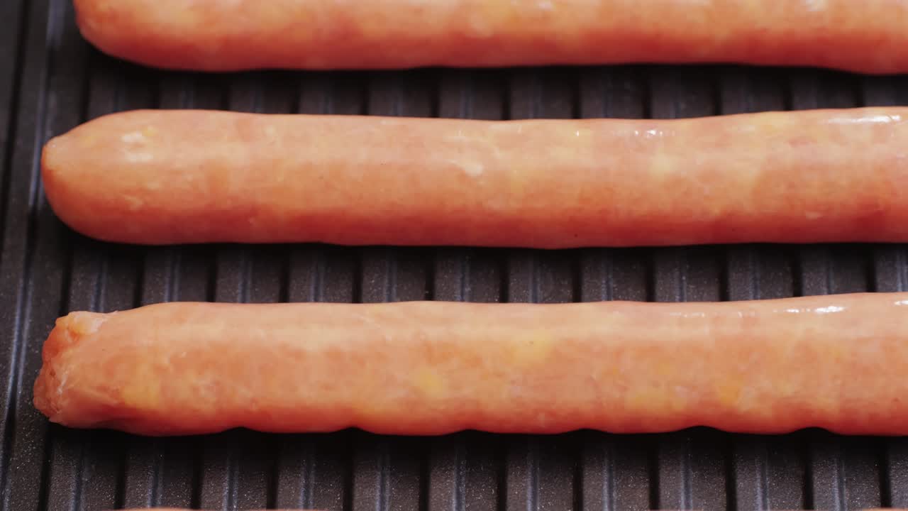 Fried sausage on a back grill close-up.Cooking corn dogs in boiling pan. Traditional asian corndog snacks street food. Korean Chinese street local market with traditional food. American fast food hot dogs with sauce on the top.