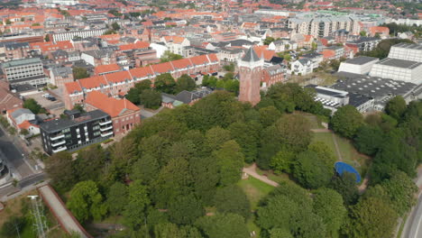 Flight-forward-over-the-city-of-Esbjerg,-Denmark-Drone-view-revealing-Water-Tower-of-Esbjerg,-an-iconic-water-tower-historical-monument-at-the-top-of-a-cliff