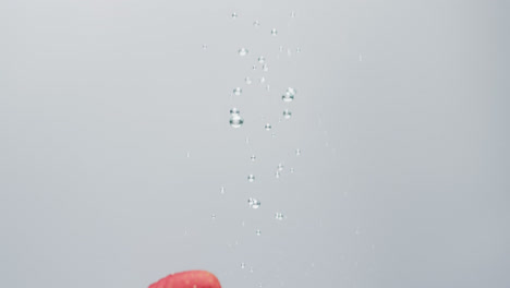 video of strawberry falling into water with copy space on white background