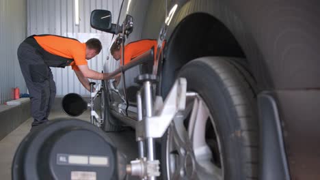 mechanic performing wheel alignment on a car in an auto repair shop