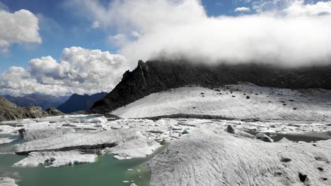 Aerial-flyover-above-a-the-icebergs-in-melted-glacier-lake-in-remote-parts-of-the-Swiss-Alps-on-a-sunny-day