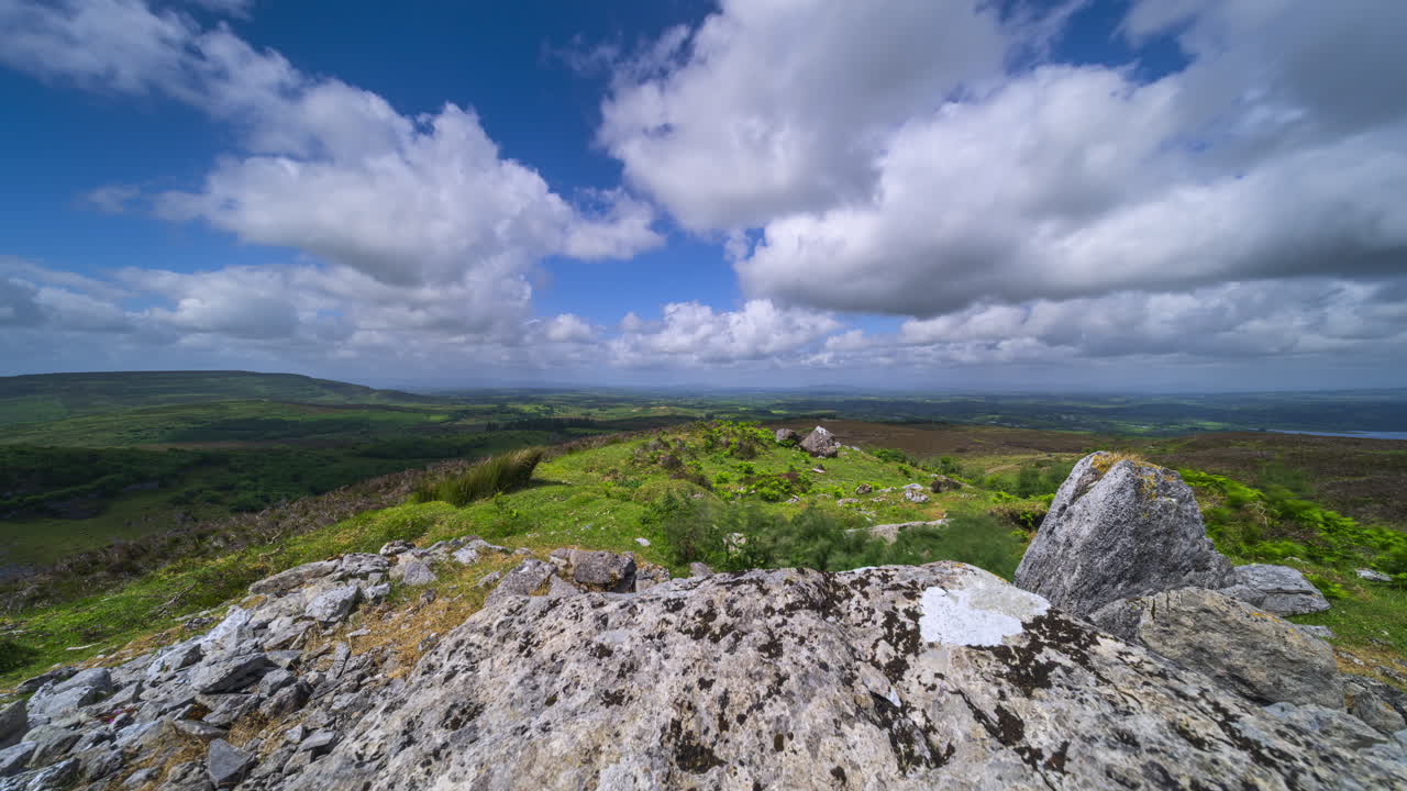 İrlanda, Sligo bölgesindeki Carrowkeel'den güneşli ve bulutlu bir günde kayalık oluşumların ön planda, tepelerin ise uzakta olduğu kırsal manzaranın hızlandırılmış çekimi