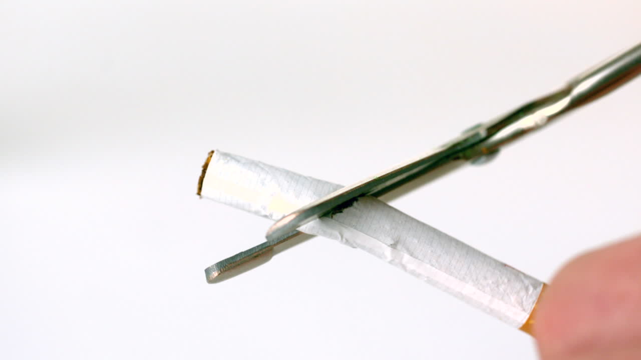 tijeras cortando un cigarrillo por la mitad