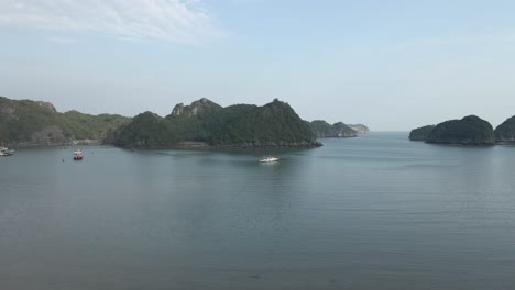 Vuelo-Aéreo-Bajo-Desde-La-Playa-Hasta-Un-Gran-Barco-Turístico-Amarrado-En-La-Bahía-De-Ha-Long