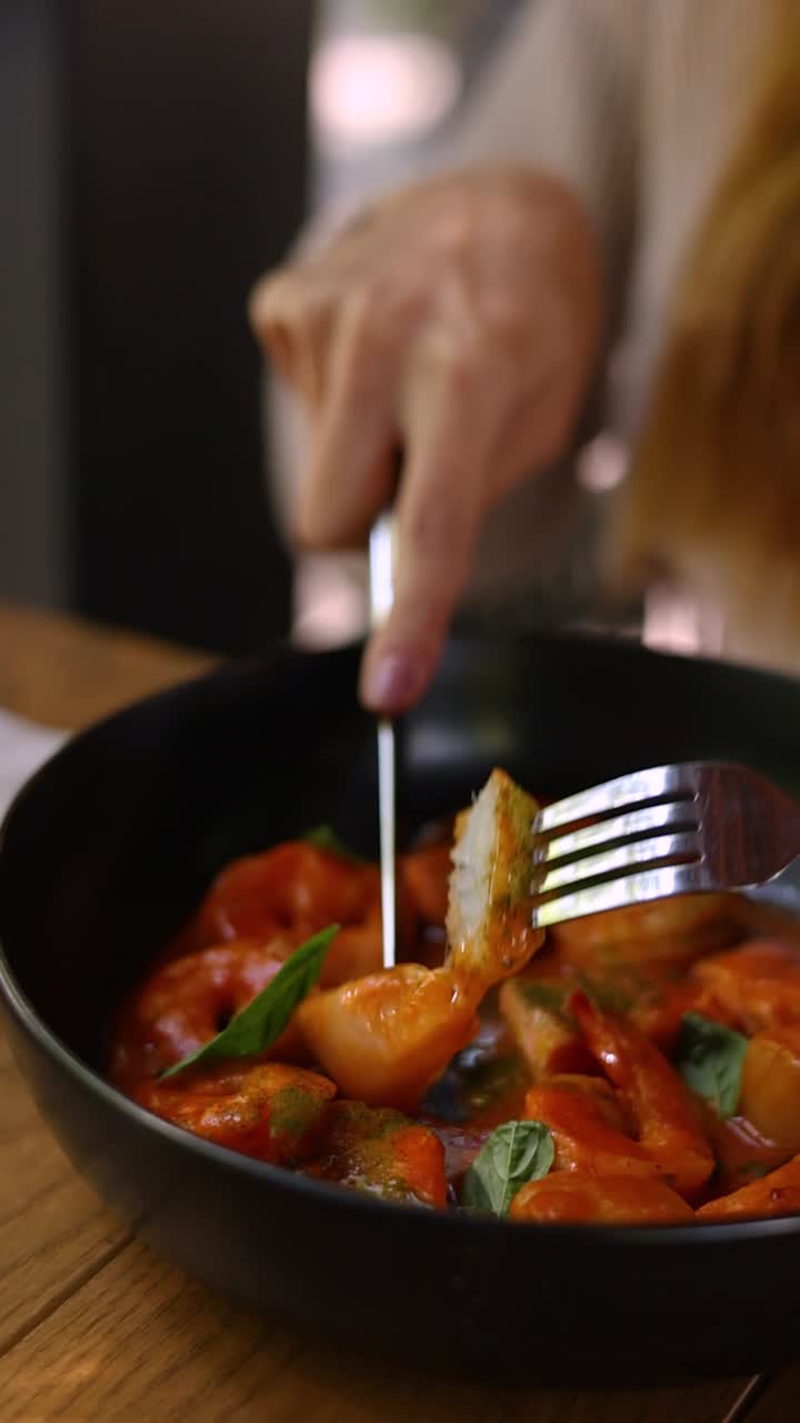 mujer comiendo gnocchi con salsa de tomate
