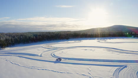 Aerial-view-above-vehicle-parked-at-start-of-freezing-Swedish-driving-track-among-woodland-mountain-scenery-at-sunrise