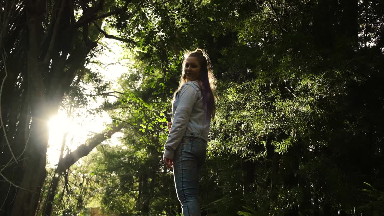 Young Caucasian girl in sunlit woodland forest wilderness freedom independence concept slow push in to closeup