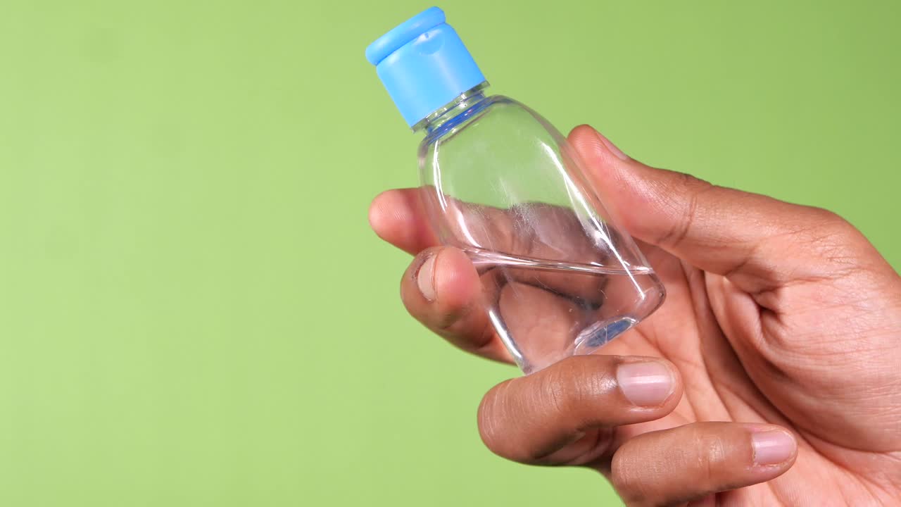persona que sostiene una pequeña botella de desinfectante para manos