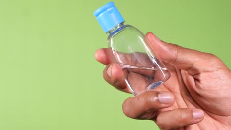 persona que sostiene una pequeña botella de desinfectante para manos