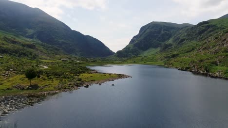 a low-flying drone shot over a lake through the gap of dunloe of killarney national park in ireland