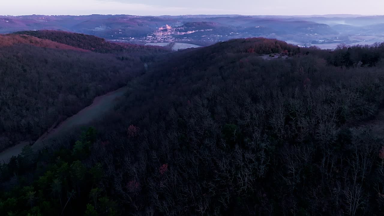 Ch&acirc;teau de Beynac at sunrise, wide view over the forest giving blue and pink colors