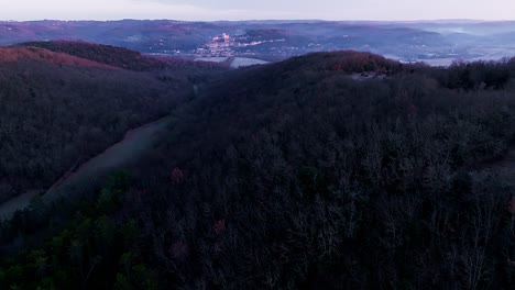 Château-de-Beynac-at-sunrise,-wide-view-over-the-forest-giving-blue-and-pink-colors