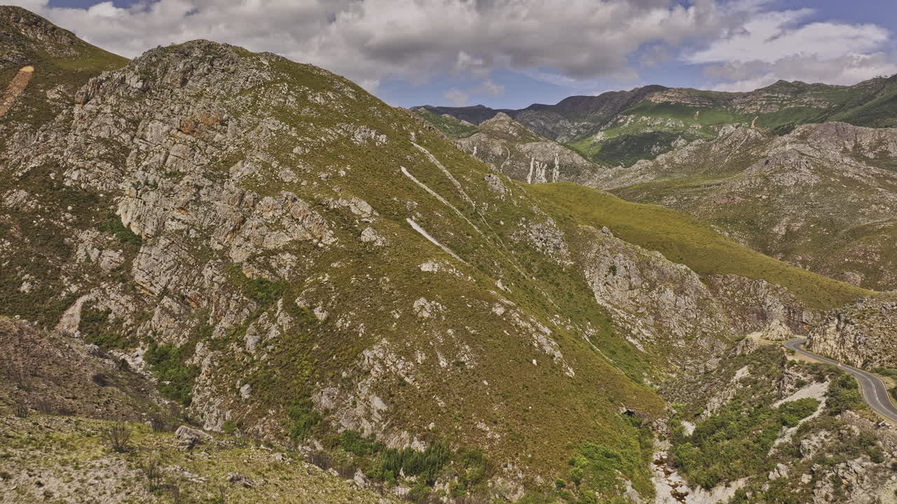 Franschhoek, Sudafrica, ripresa aerea v17, volo radente su Lambrechts Rd che cattura lo splendido paesaggio montano della Riserva Naturale di Theewaters sotto un cielo parzialmente nuvoloso - Ripresa effettuata con Mavic 3 Pro Cine - 6 gennaio 2024