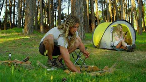 Man-preparing-bonfire-in-the-forest-on-a-sunny-day-4k