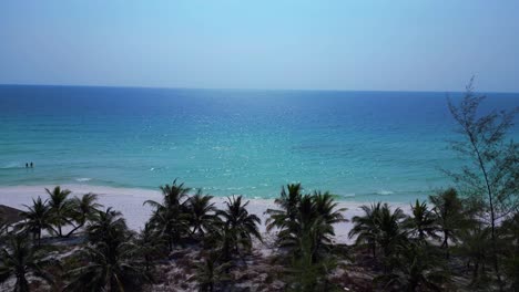 sok san beach with turquoise water washing the white sand, surrounded by palm trees and tropical vegetation. breathtaking aerial view flight static tripod hovering drone