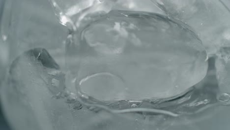 liquid filling glass with ice and rising bubbles