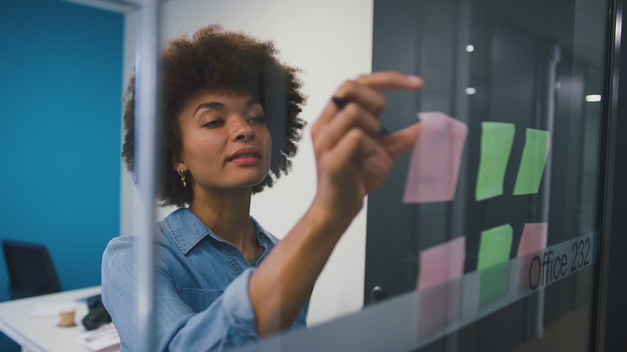Young Businesswoman Working In Modern Office Looking At Transparent Screen With Sticky Notes
