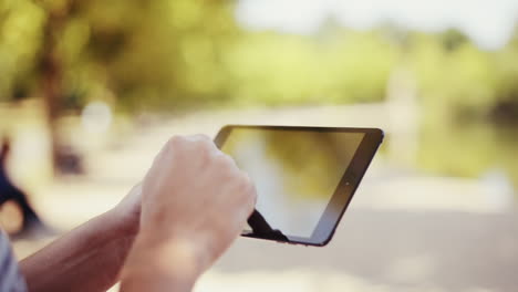 man using digital tablet computer ipad outdoors in nature