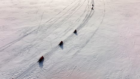 vista aérea de personas montando motos de nieve en el suelo congelado del glaciar myrdalsjokull en islandia