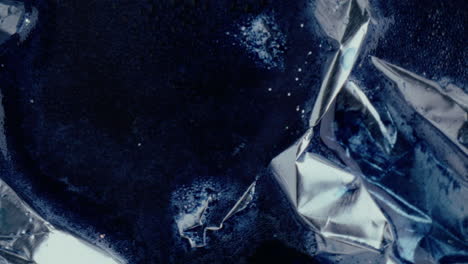 crumpled foil with blue liquid and glitter