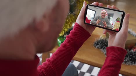 Caucasian-man-with-santa-hat-using-smartphone-for-christmas-video-call-with-smiling-man-on-screen