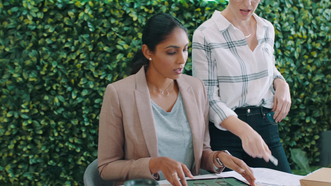Due donne d'affari che collaborano con un tablet digitale in un ufficio moderno
