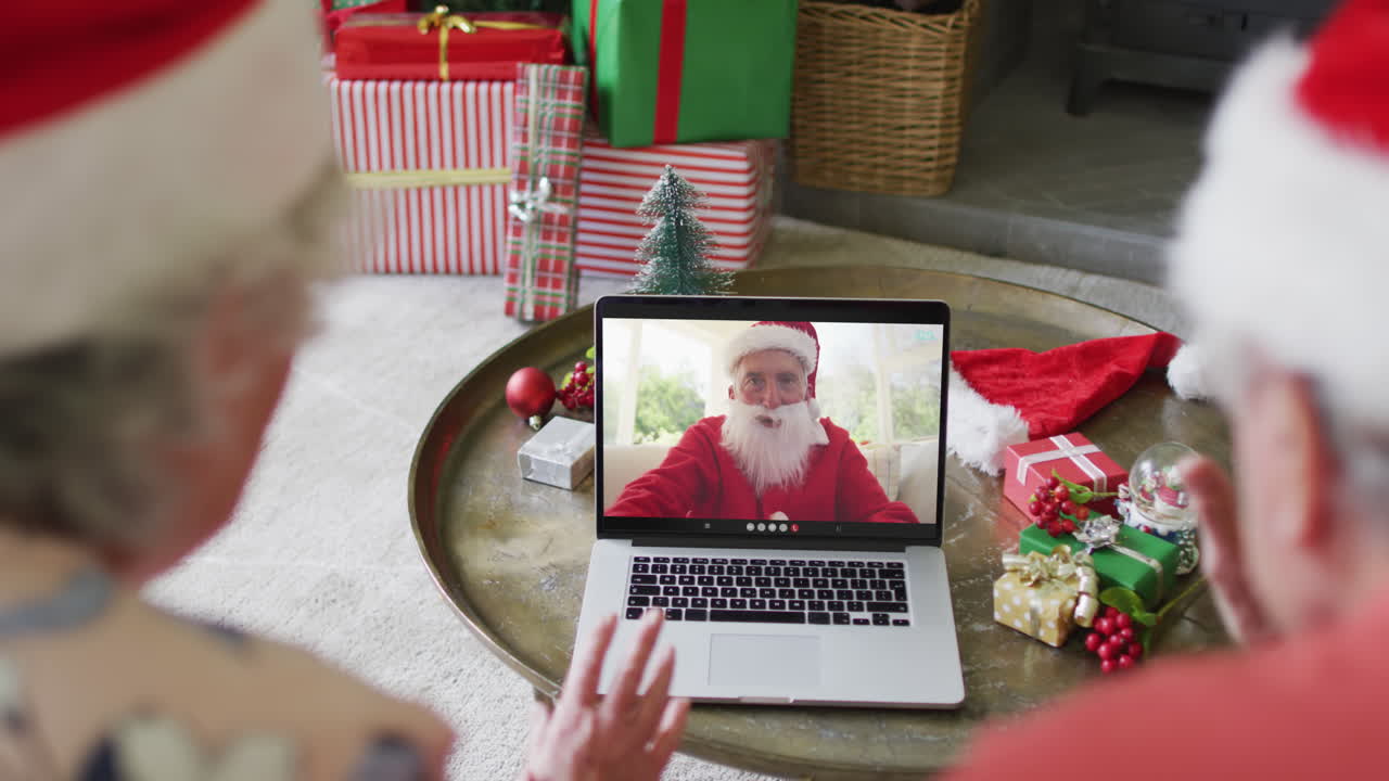una pareja caucásica de alto nivel usando una computadora portátil para una videollamada de navidad con happy santa en la pantalla