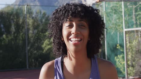 portrait of happy african american female basketball player on sunny court, in slow motion