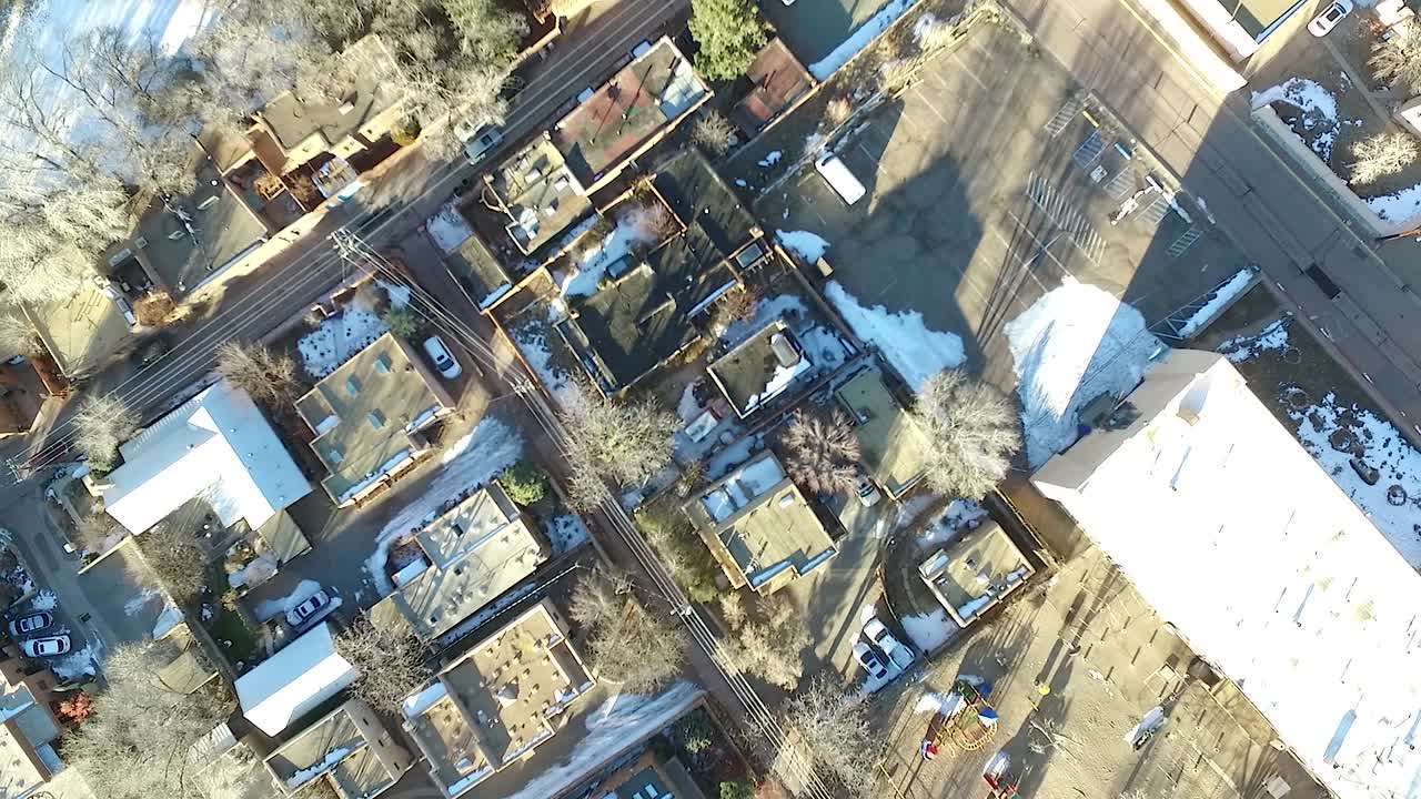 Aerial drone footage spinning over a residential neighborhood in Santa Fe, New Mexico, during winter with visible snow patches and warm late-day light