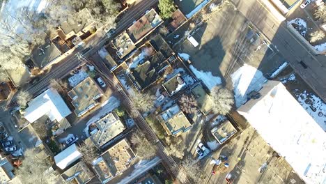 aerial drone footage spinning over a residential neighborhood in santa fe, new mexico, during winter with visible snow patches and warm late-day light