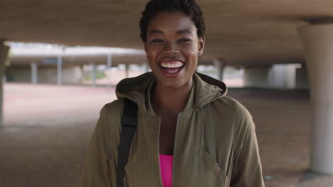 portrait of confident african american woman student smiling laughing urban background