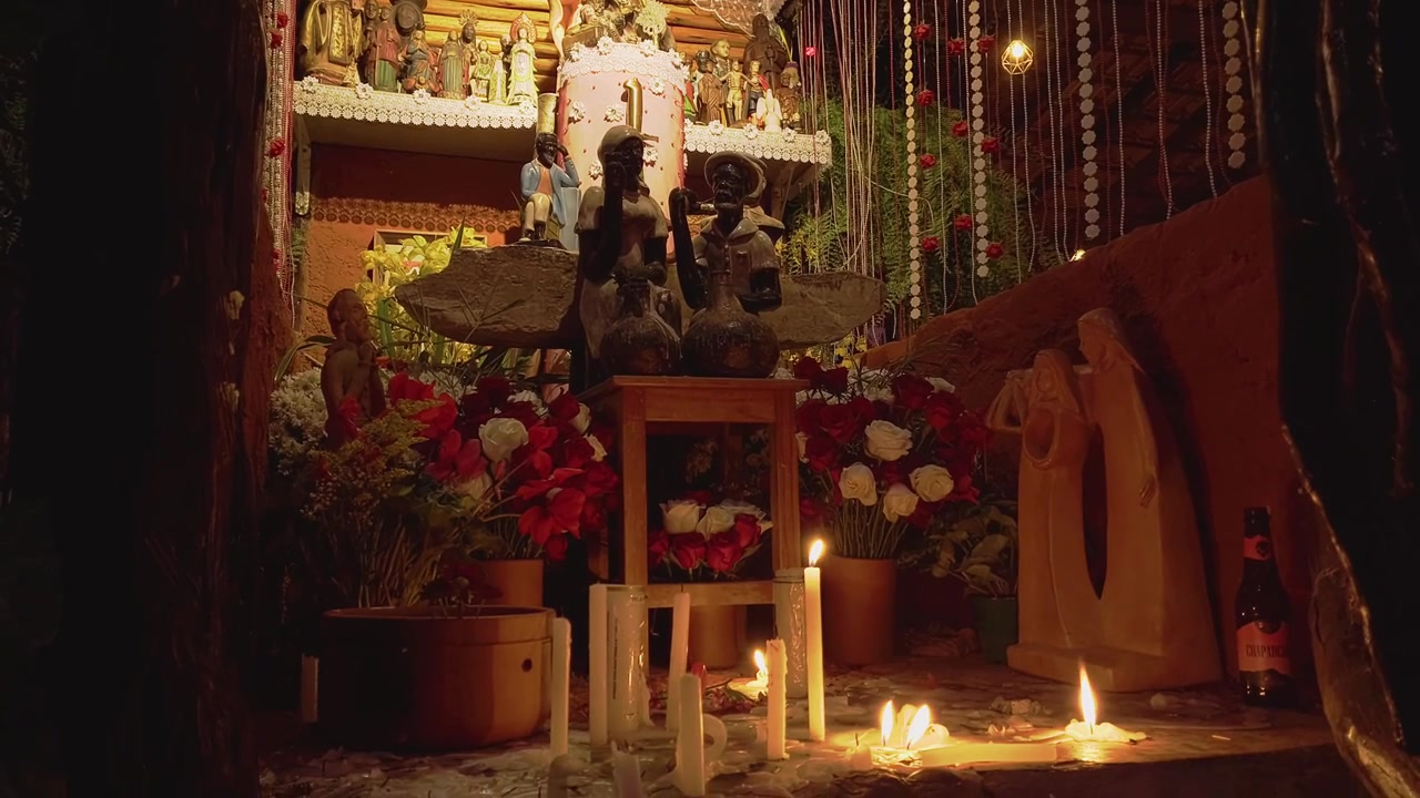 Camera pans down revealing a richly decorated devotional altar with sacred statues, candles, flowers and ceremonial ornaments inside a community sanctuary in Chapada dos Veadeiros, Goiás, Brazil.