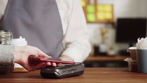 pagar con un primer plano de teléfono inteligente, utilizando la tecnología nfc en un restaurante. el cliente paga por teléfono móvil, tecnología sin contacto, pago sin contacto en una cafetería.