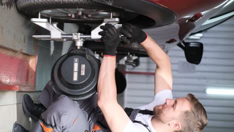 mechanic performing wheel alignment on a car in an auto repair shop