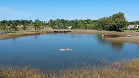 drone view-cityscape- people paddling boat-kayak in a lake with the grey grass background