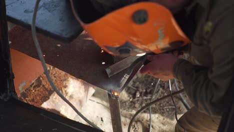 man welding a piece of metal wearing a mask for light protection, slowmo