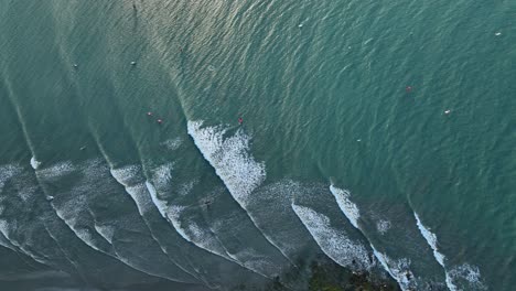 turquoise waves form parallel lines and break near the shore in jericoacoara, brazil. slow motion a top-down drone aerial