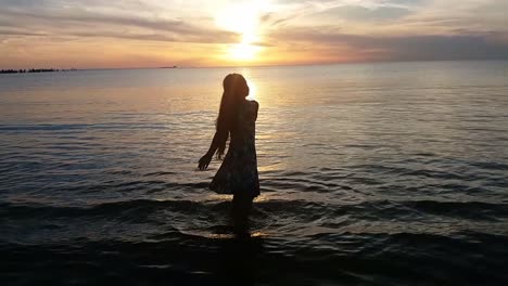 silhouette of young lady dancing on the beach at sunset