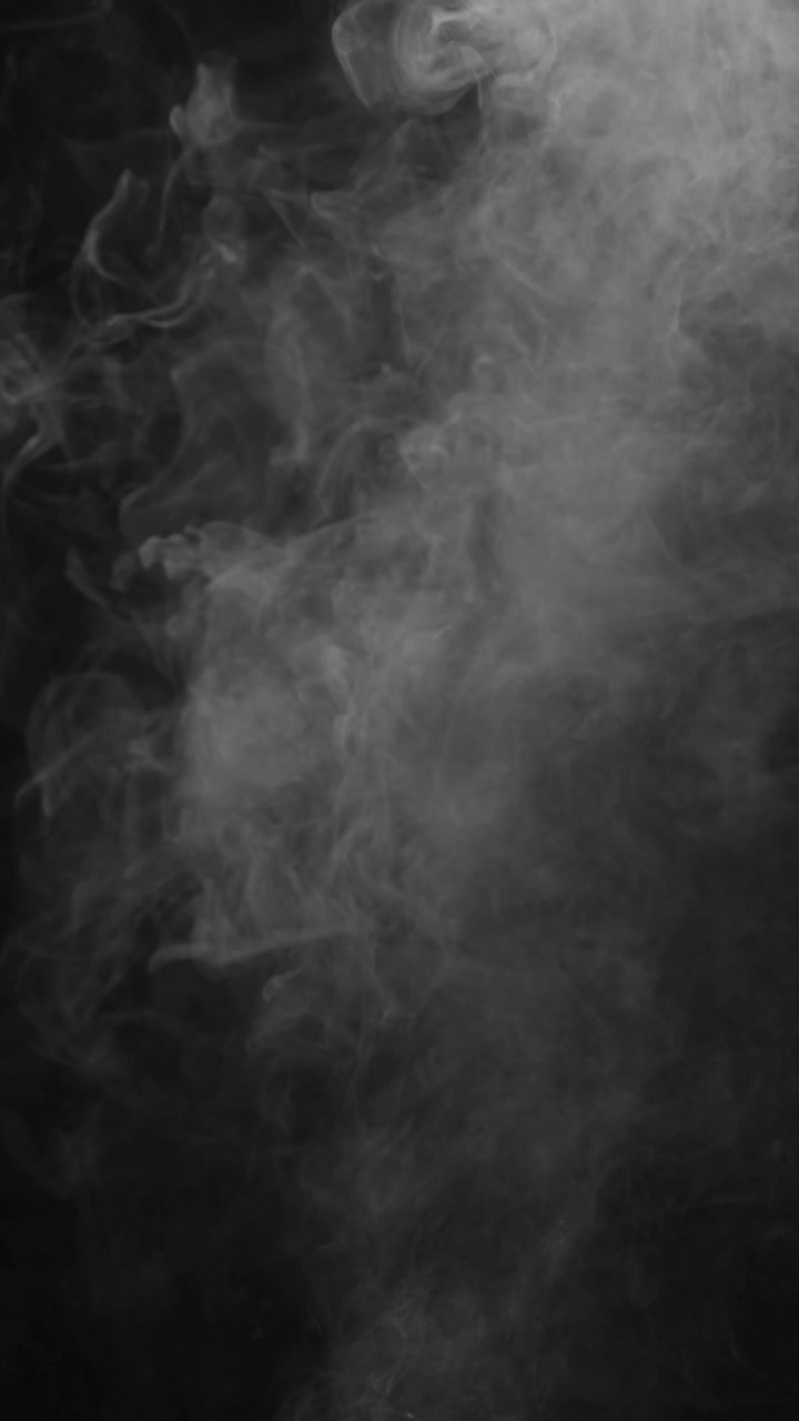 Una fitta e densa nuvola di nebbia bianca si agita lentamente sul lato sinistro di uno schermo nero. Crea un'atmosfera potente, suggestiva o tempestosa, formato verticale