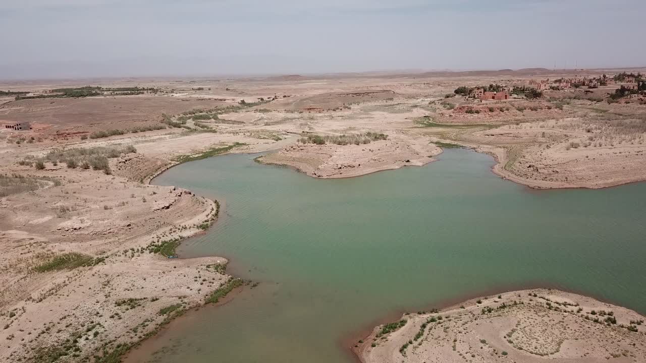 Turkuaz bir su kütlesinin kurak kumlu bir arazide kıvrılarak aktığı kuşbakışı çekim. Bu çekim görüntüsü, değerli su kaynakları ile kurak Kuzey Afrika çöl arazisi arasındaki zıtlığı vurguluyor
