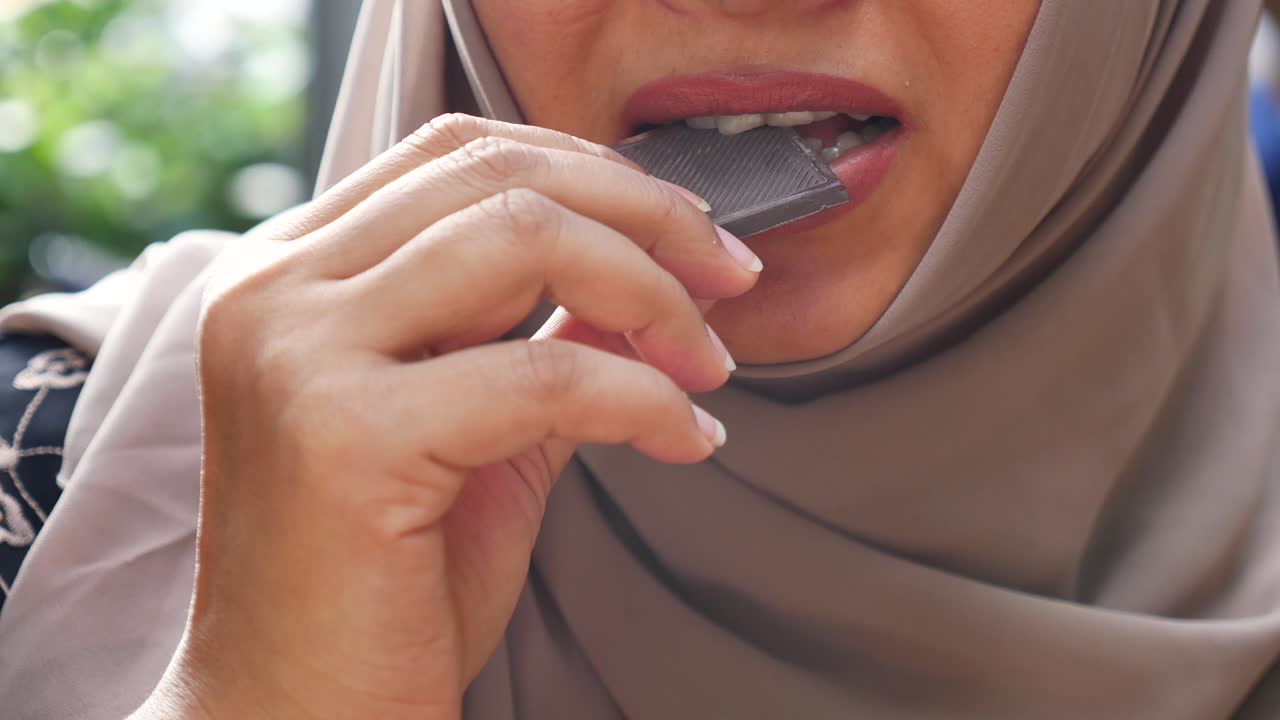 A woman in a hijab eating chocolate