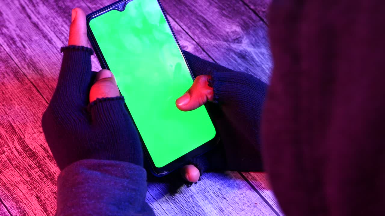 persona que utiliza un teléfono inteligente con pantalla verde en la oscuridad