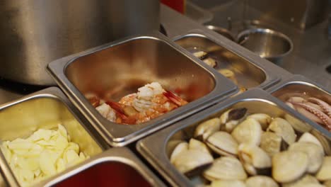 ingredientes de mariscos para la preparación de sopa de pasta mediterránea en una cocina de restaurante profesional