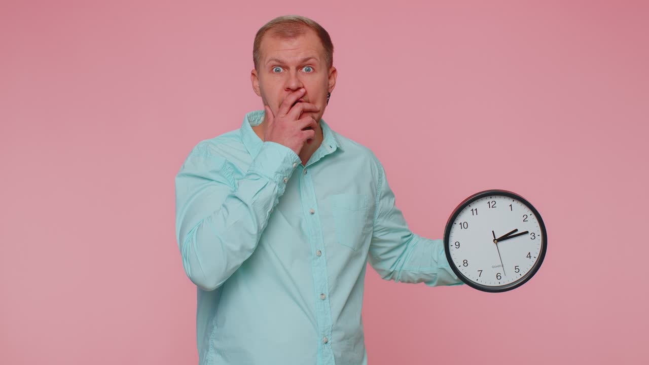 Un homme confus avec de l'anxiété, vérifiant l'heure sur l'horloge, en retard au travail, en retard sur la date limite.