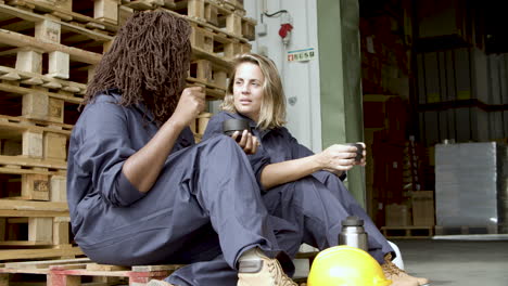 Diverse-workers-talking-and-drinking-coffee-while-sitting-at-wooden-platform