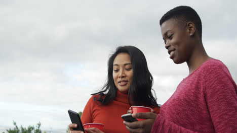 Mujeres-Jóvenes-Que-Usan-Teléfonos-Inteligentes-En-Una-Azotea