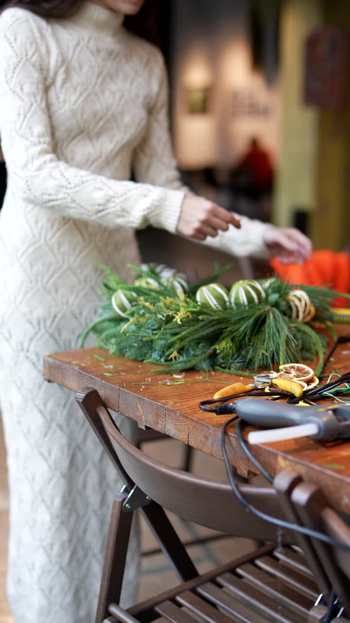 una mujer haciendo una corona de navidad.